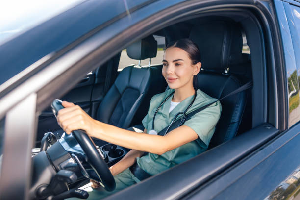 medical occupation. smiling female doctor sitting in the car on a drivers seat