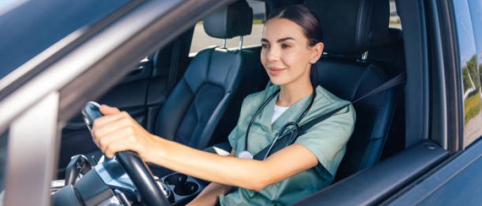 medical occupation. smiling female doctor sitting in the car on a drivers seat